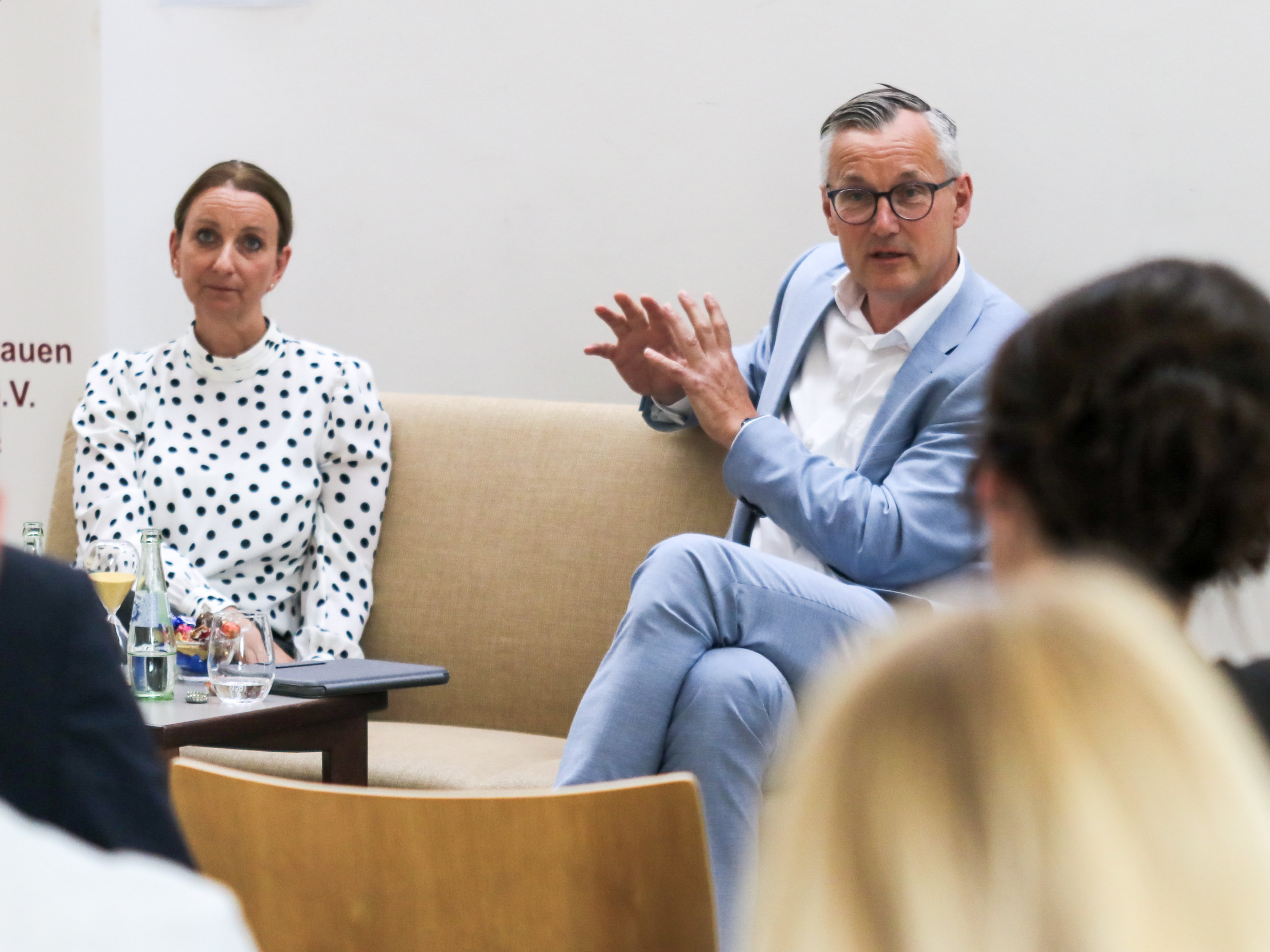 Anna-Christina Rex (CDU und Axel Tschersich (SPD) sitzen auf einem Sofa vor dem Publikum im Paulushaus recklinghausen.